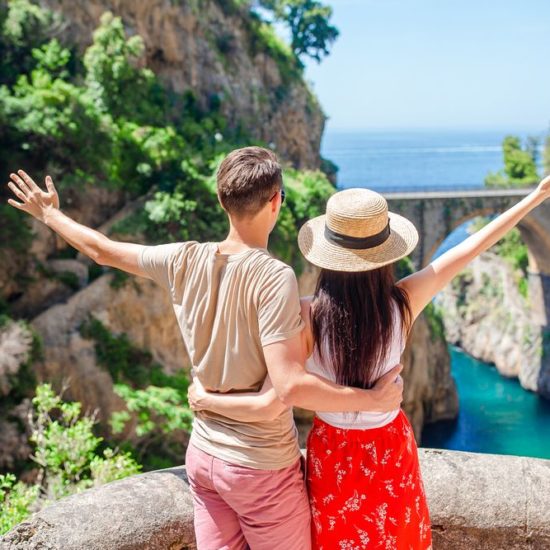 Happy couple enjoy the amazing view of Fiordo di Furore. Cala di Furore beach, bridge over the gorge Fiordo di Furore.