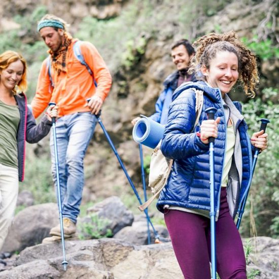 Group of friends with backpacks doing trekking excursion on mountain - Young tourists walking and exploring the nature - Trekker, hike and travel people concept