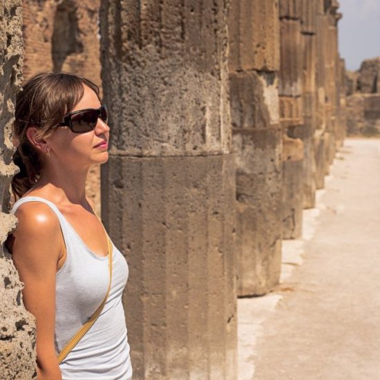 Young women behind the ruins of the city of Pompeii. Italy.