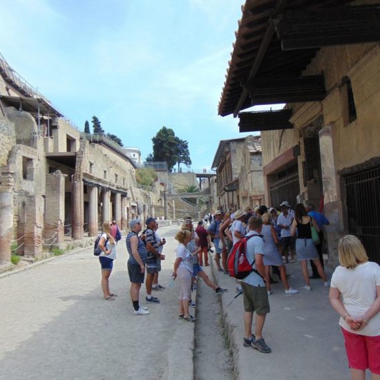 people standing in front on a old shop of Ercolano ruins