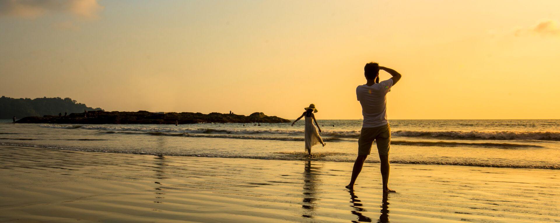 Vacation Photographer is taking picture of a young lady on the beach